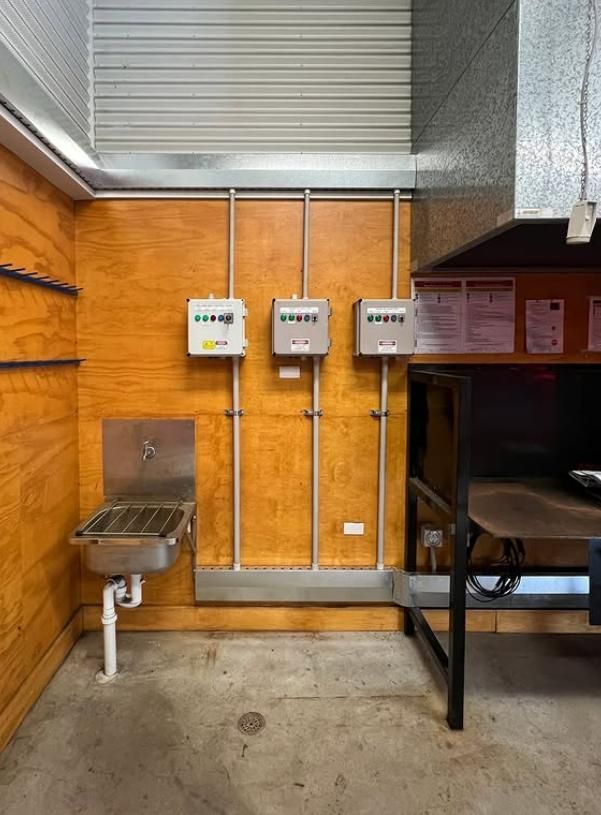 Stainless Steel Sink and Electrical Boxes on a Wood Panel Wall — DMP Electrical Contractors In Mandalong, NSW