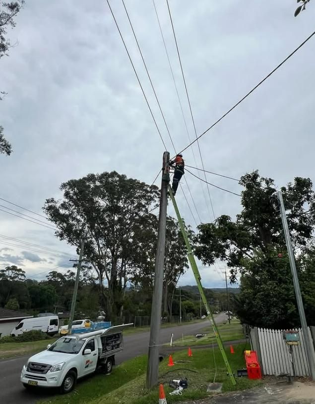 Lineman on a Ladder Working on Power Lines Attached to a Utility Pole — DMP Electrical Contractors In Mandalong, NSW