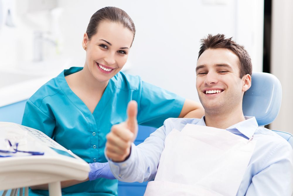 A Dentist is Giving a Thumbs Up to a Patient in a Dental Chair — Parap Family Dental in Parap, NT