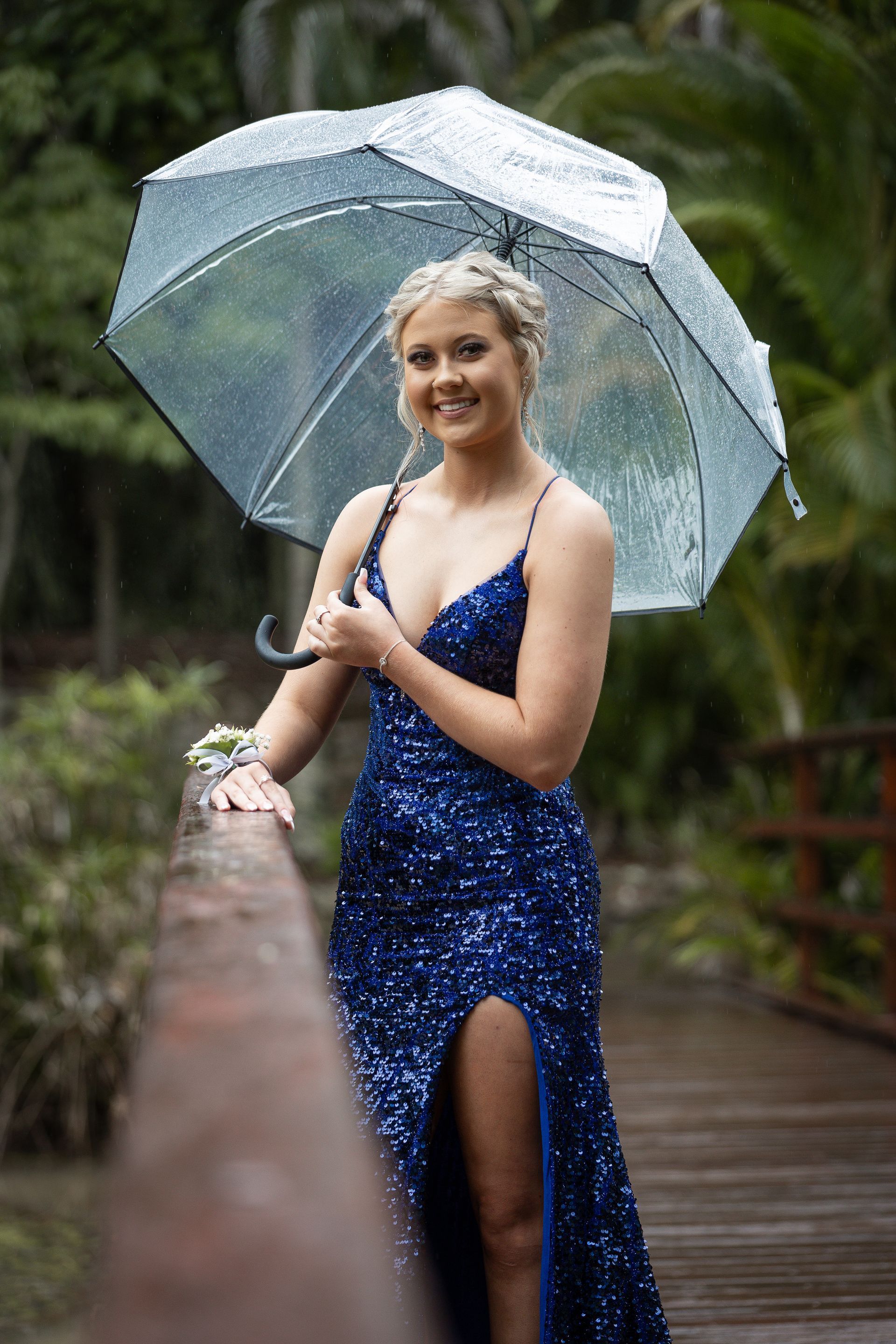 A woman in a blue sparkly dress standing on a bridge holding an umbrella — Jack West Photography In Kawungan, QLD