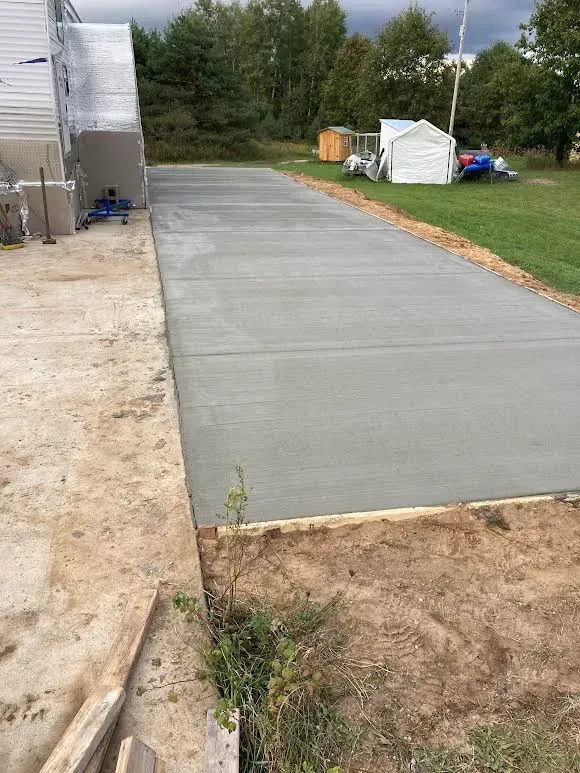 A concrete driveway is being built in the backyard of a house.