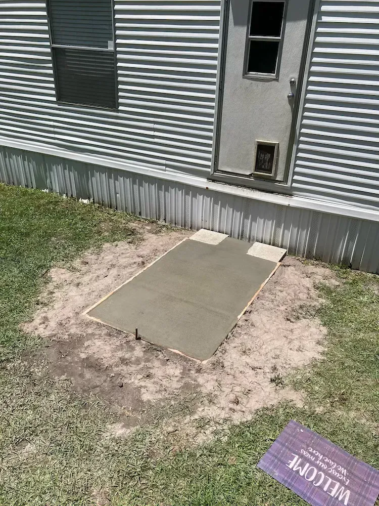 A concrete walkway is being built in front of a house.