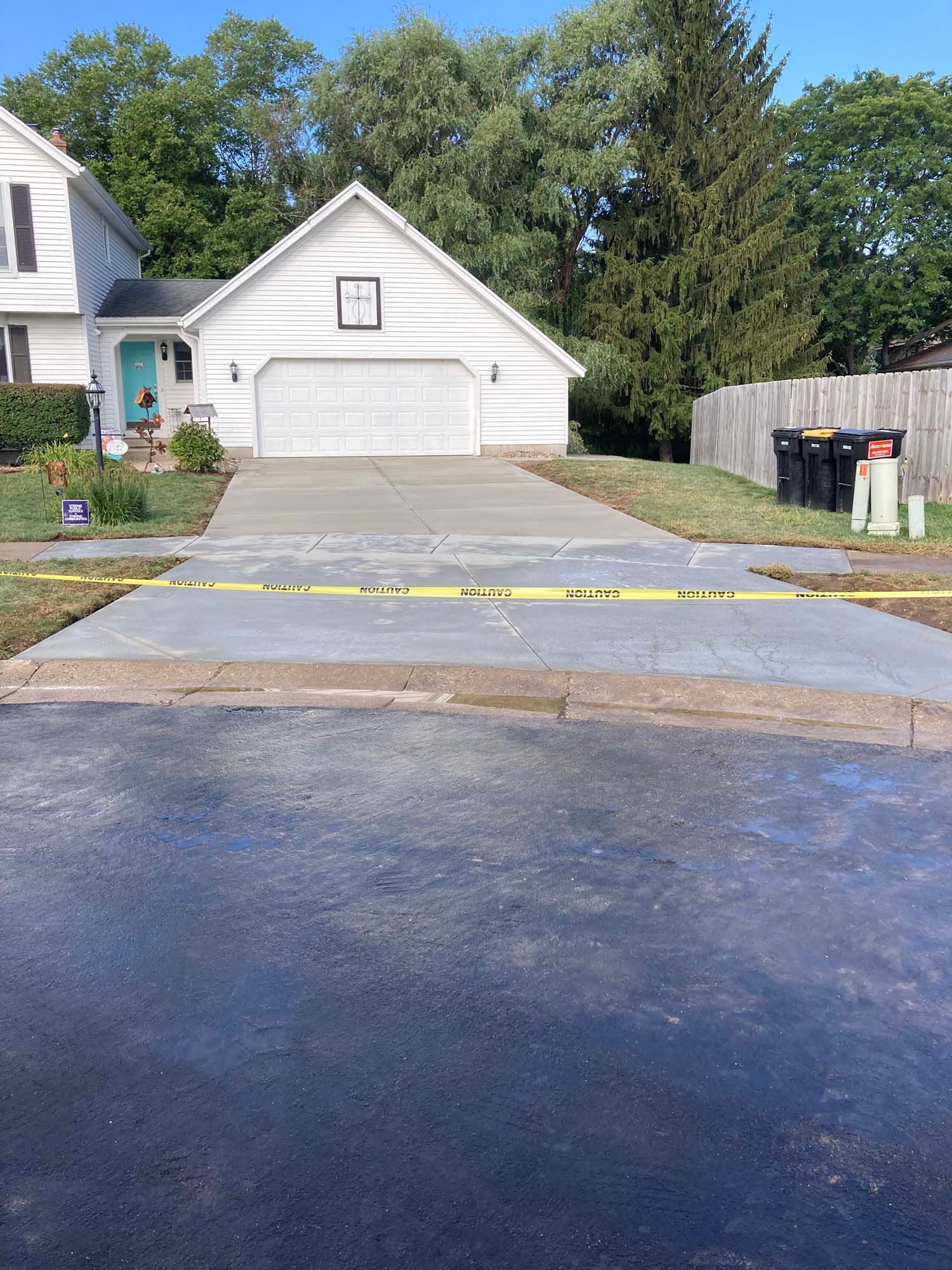 A concrete driveway with a wooden fence in the background.