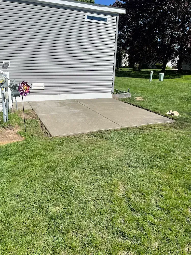 There is a concrete patio in front of a mobile home.