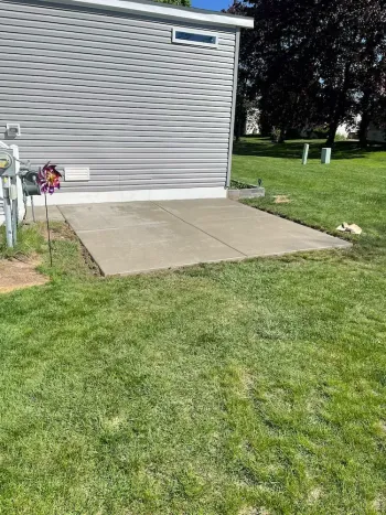 There is a concrete patio in front of a mobile home.