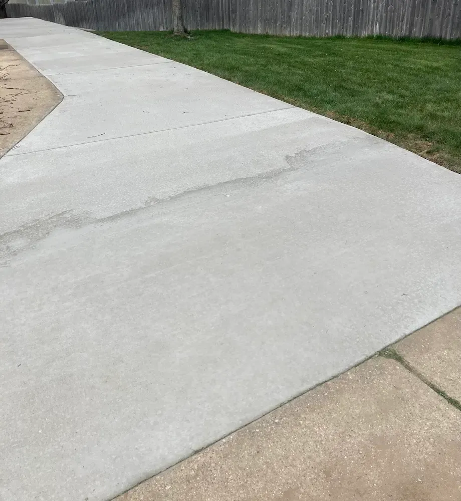 A concrete driveway with a wooden fence in the background.
