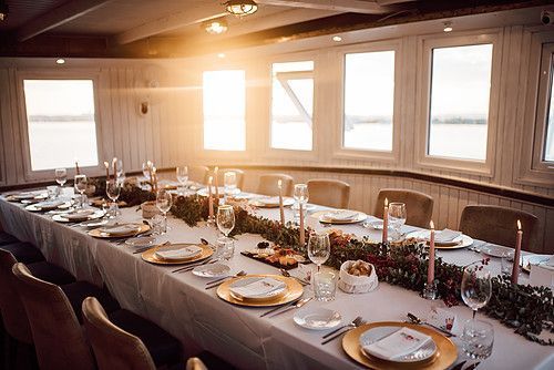 An intimate dinner setup inside the boat with elegantly arranged tables and warm lighting.