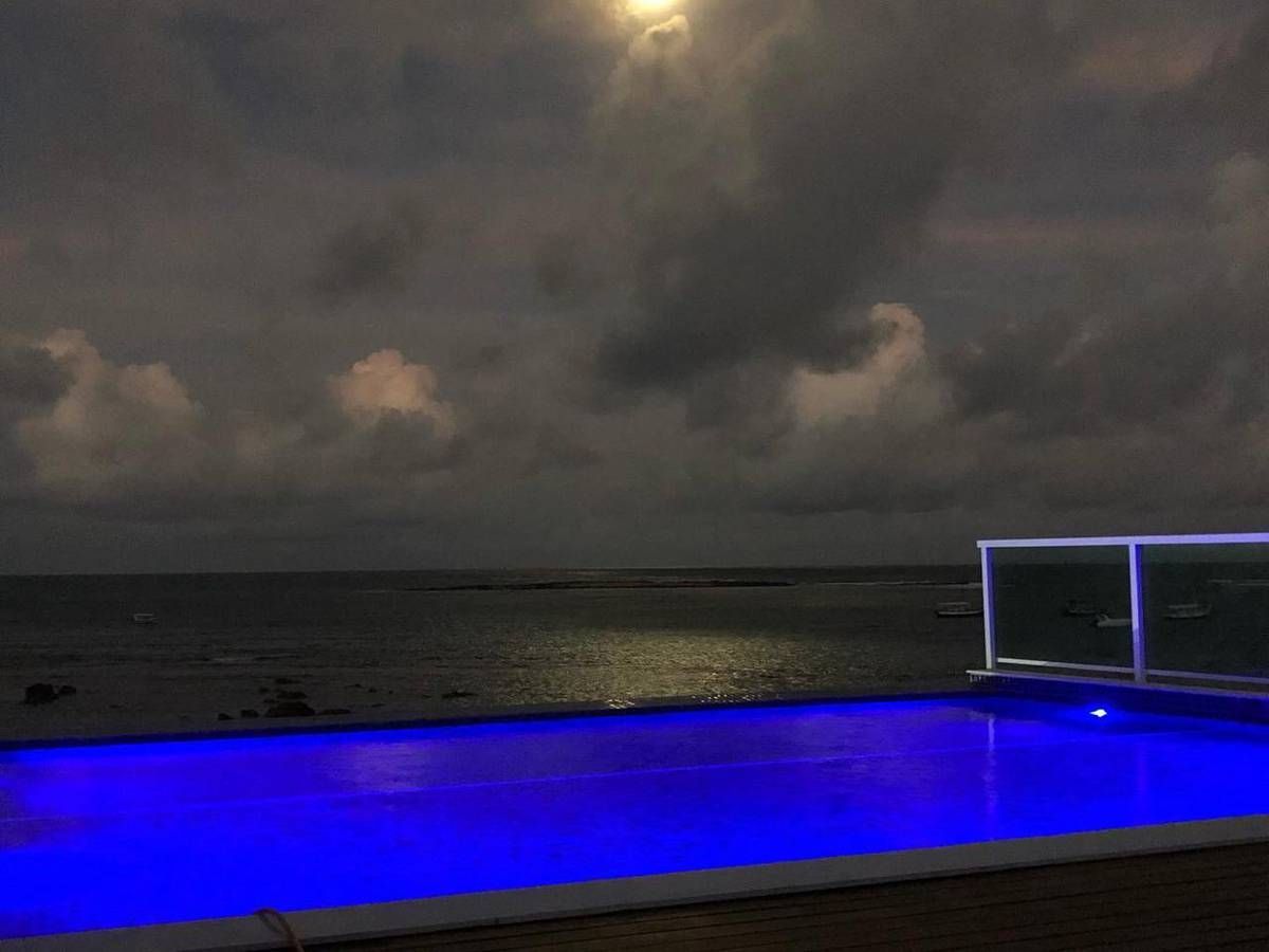 Uma piscina iluminada à noite com vista para o oceano.