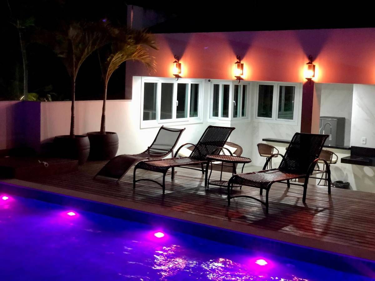 Uma piscina é iluminada à noite com luzes roxas.