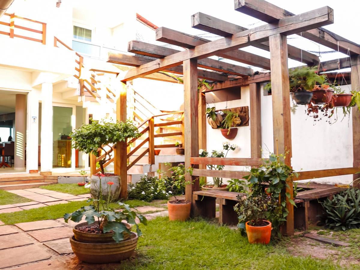 Um jardim com uma pérgola de madeira e plantas em vasos