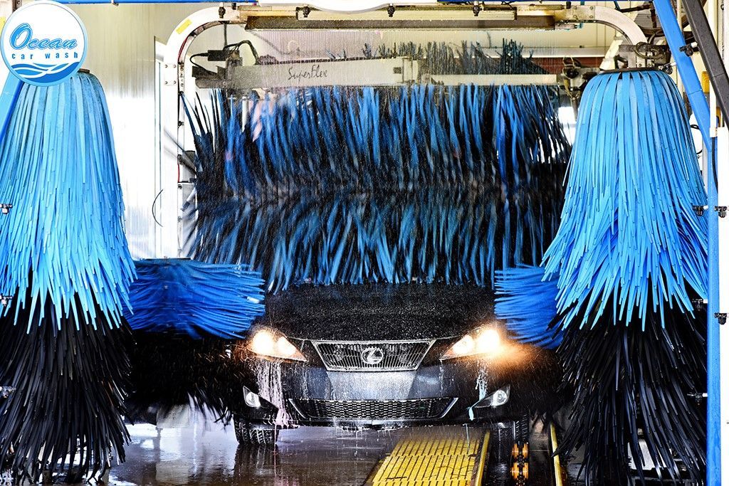 A car is going through a car wash with blue brushes.