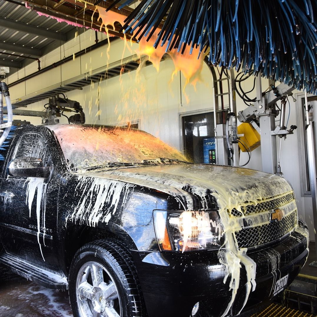 A black truck is covered in foam at a car wash