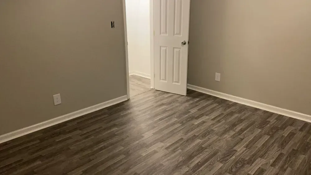 An empty room with hardwood floors and a door.