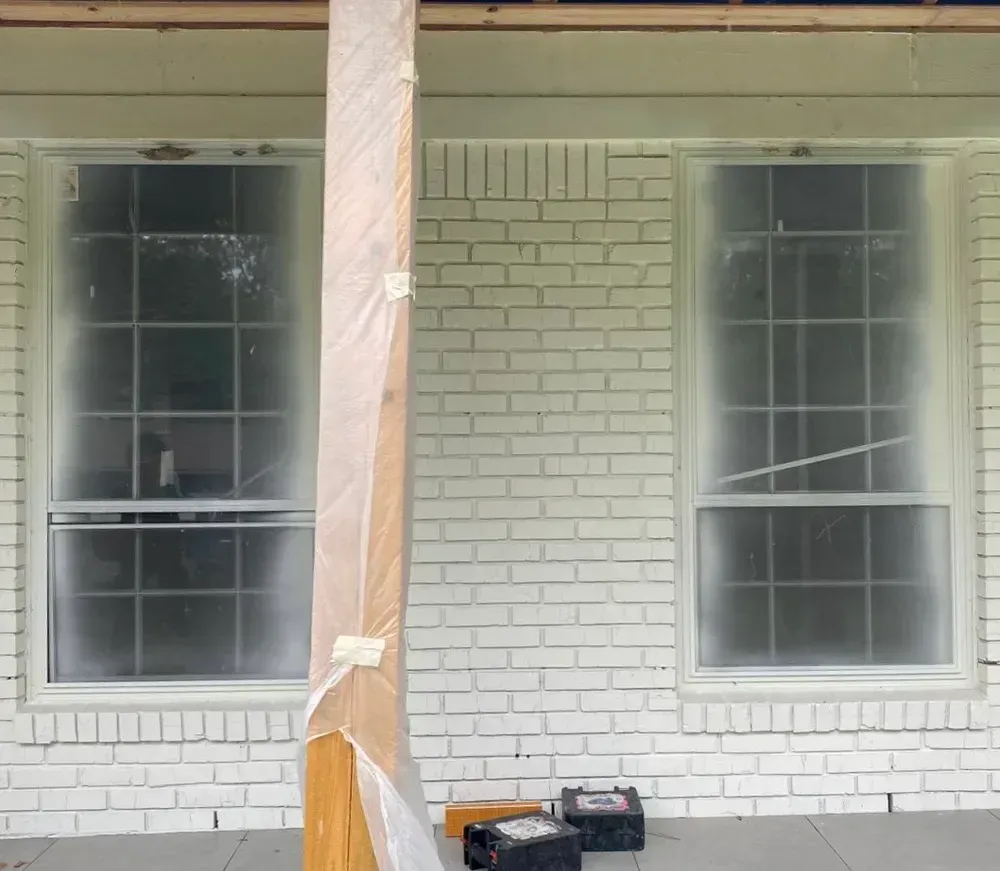 A white brick house with two windows painted white