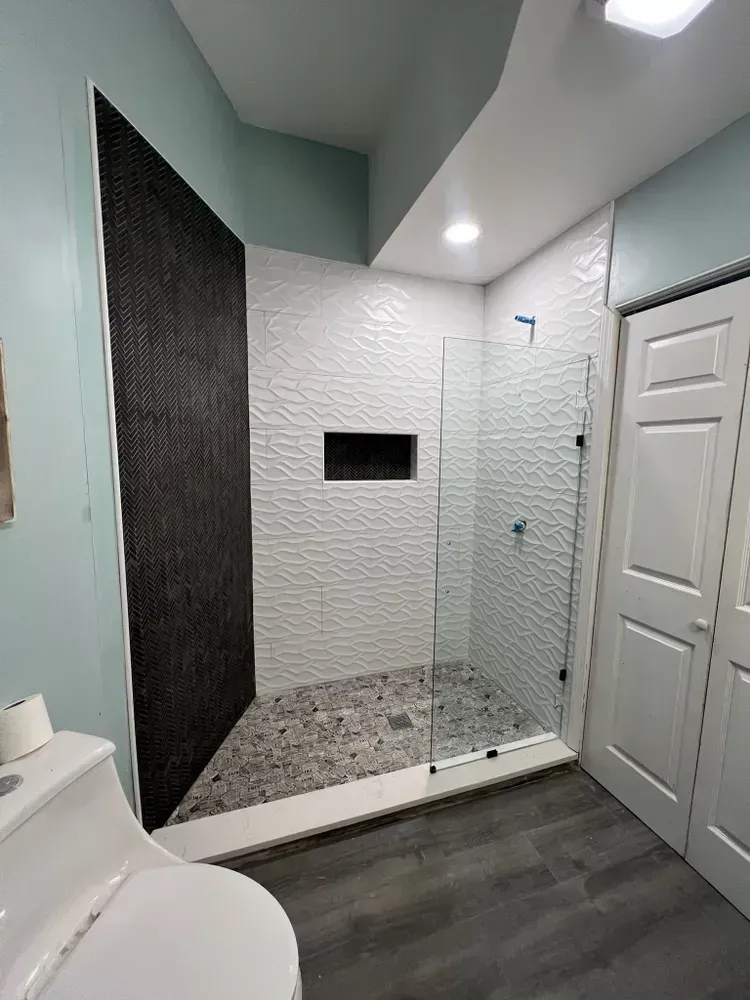A bathroom with a toilet , sink and walk in shower.