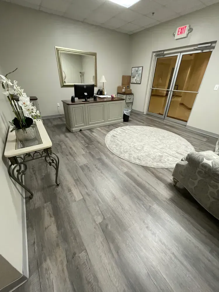 A living room with hardwood floors , a desk , a couch and a mirror.