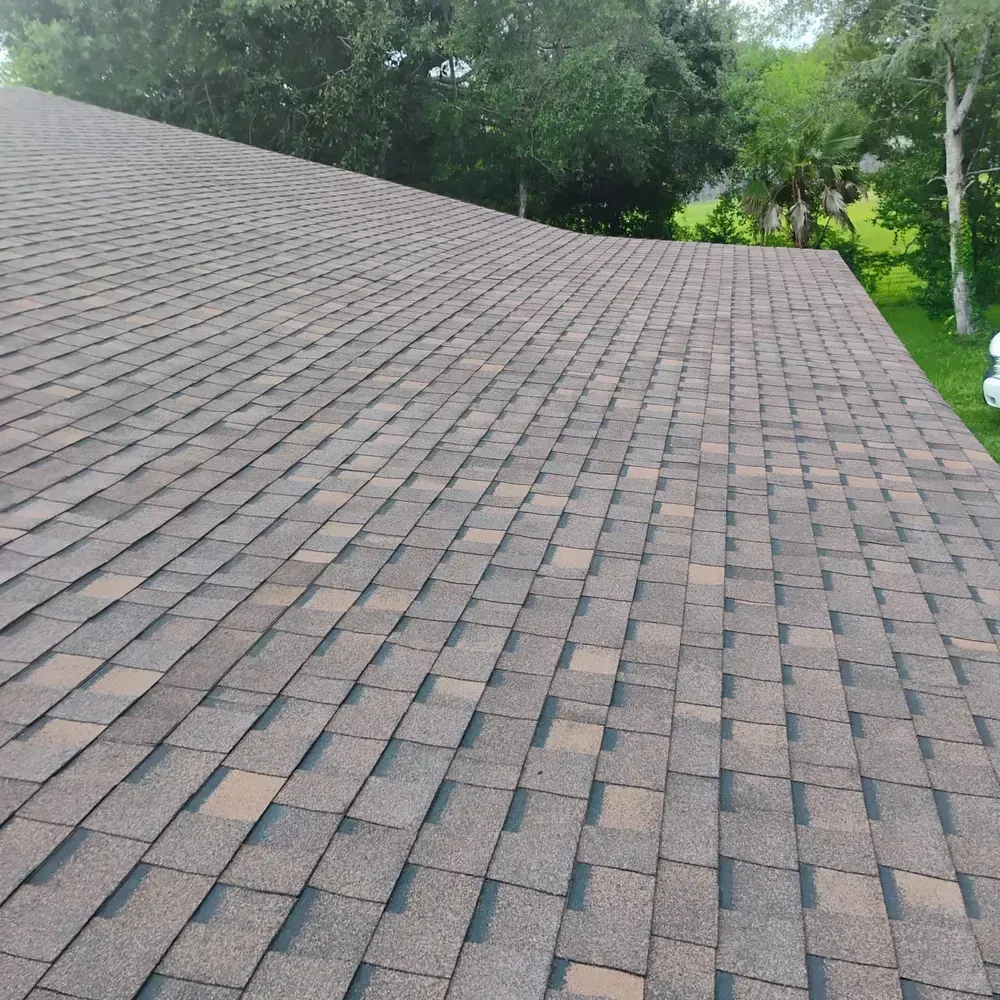 A roof with a lot of shingles and trees in the background