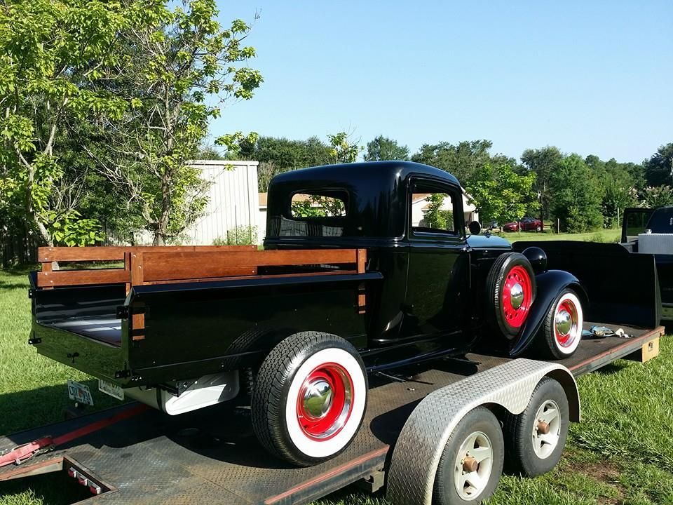 A black truck is sitting on top of a trailer.