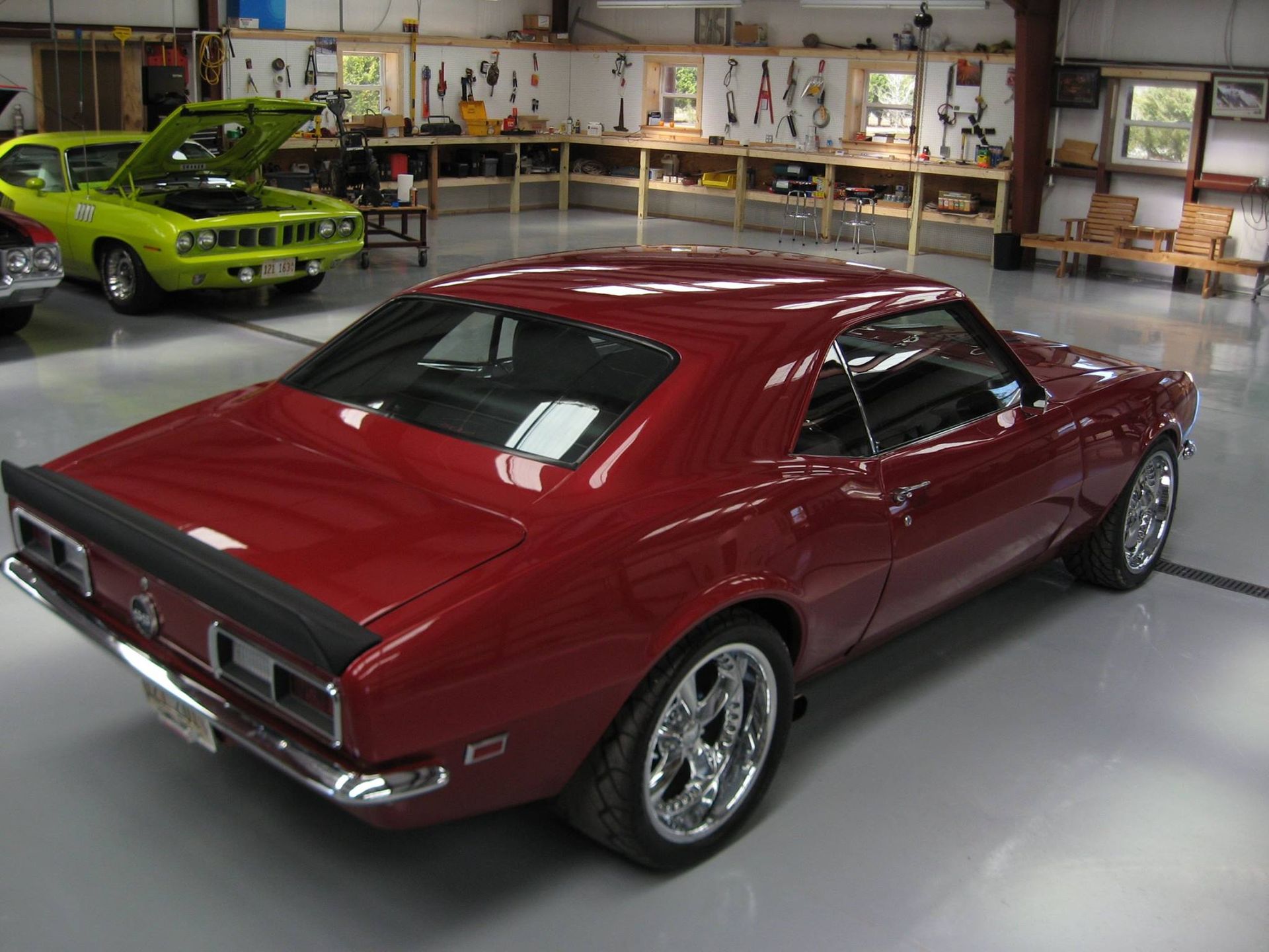 A red car is parked in a garage with other cars