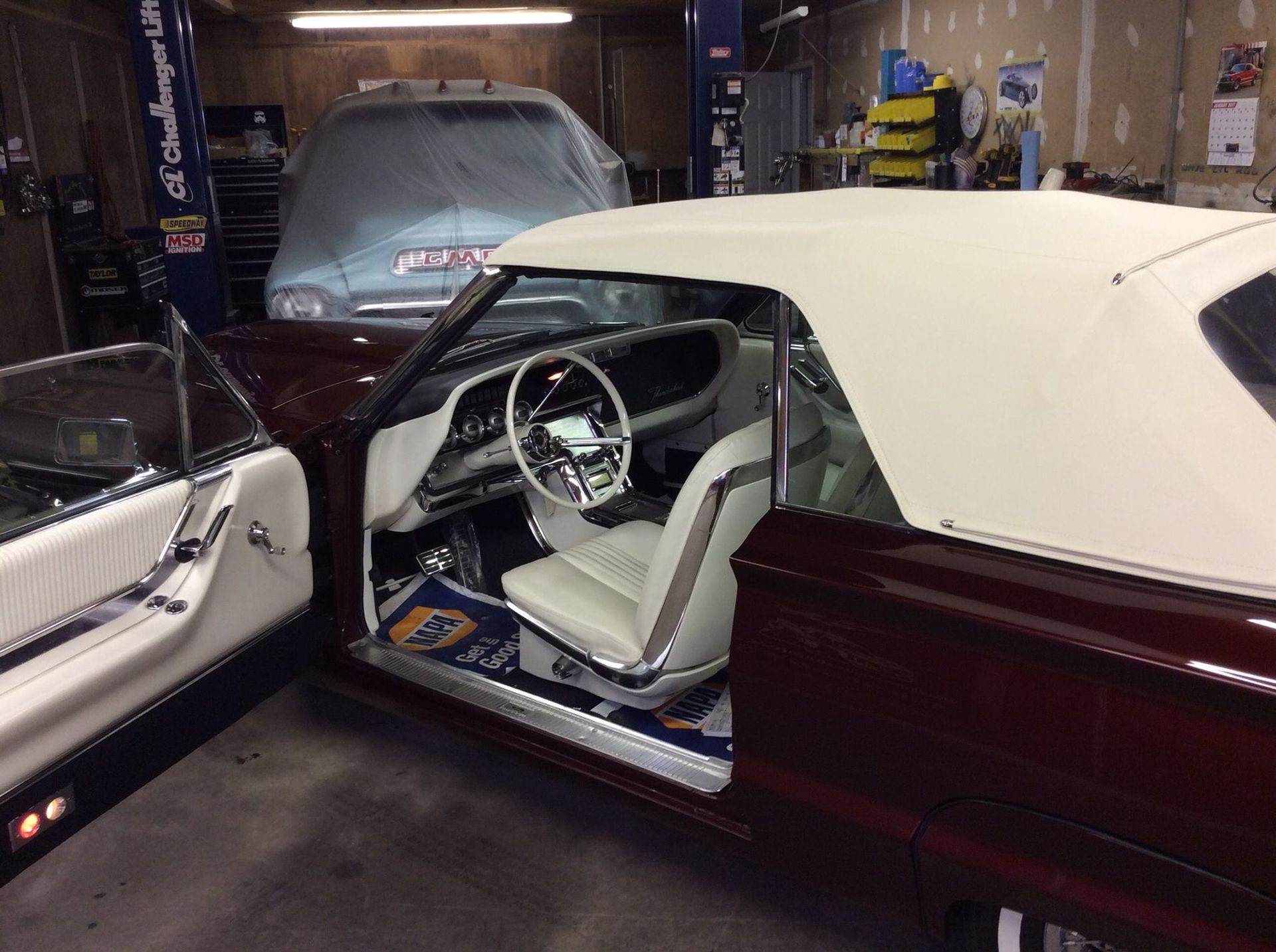 A convertible car is parked in a garage with the door open.