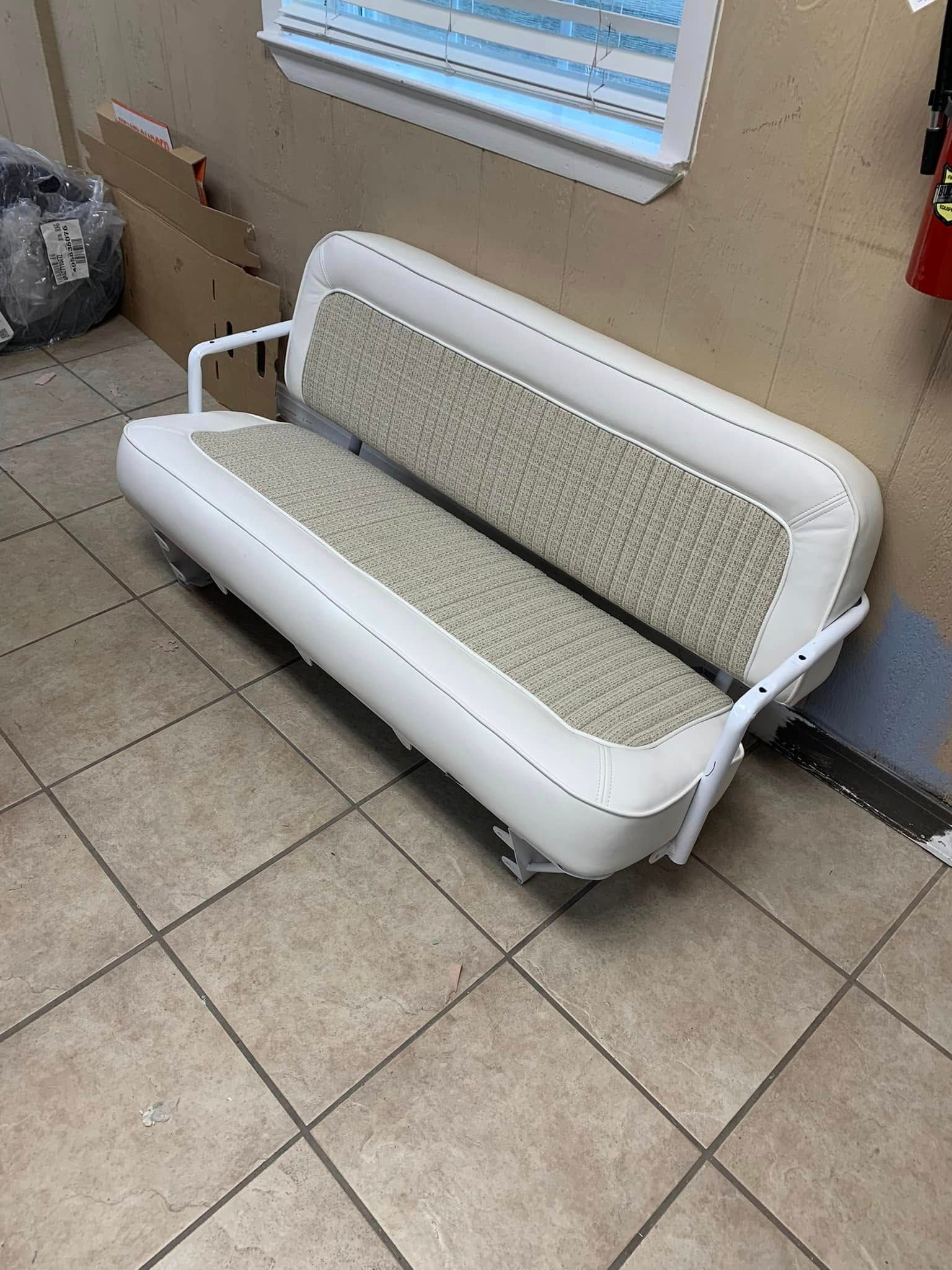 A white couch is sitting on a tiled floor next to a window.