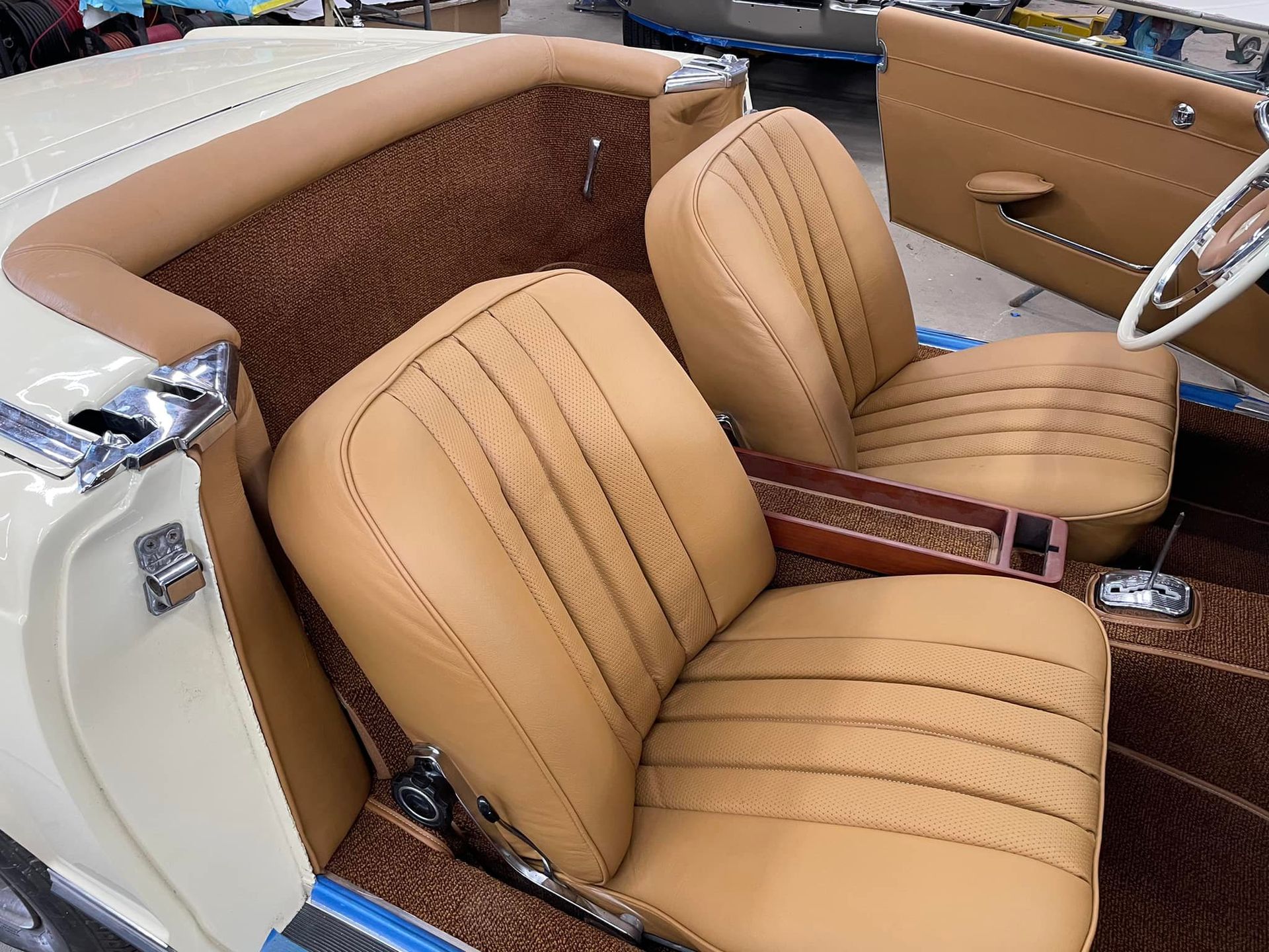 The inside of a car with tan leather seats and a steering wheel.