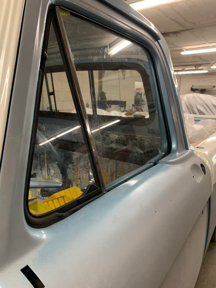 A blue truck is parked in a garage with the door open.