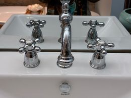 Chrome faucet and handles on a white porcelain sink.