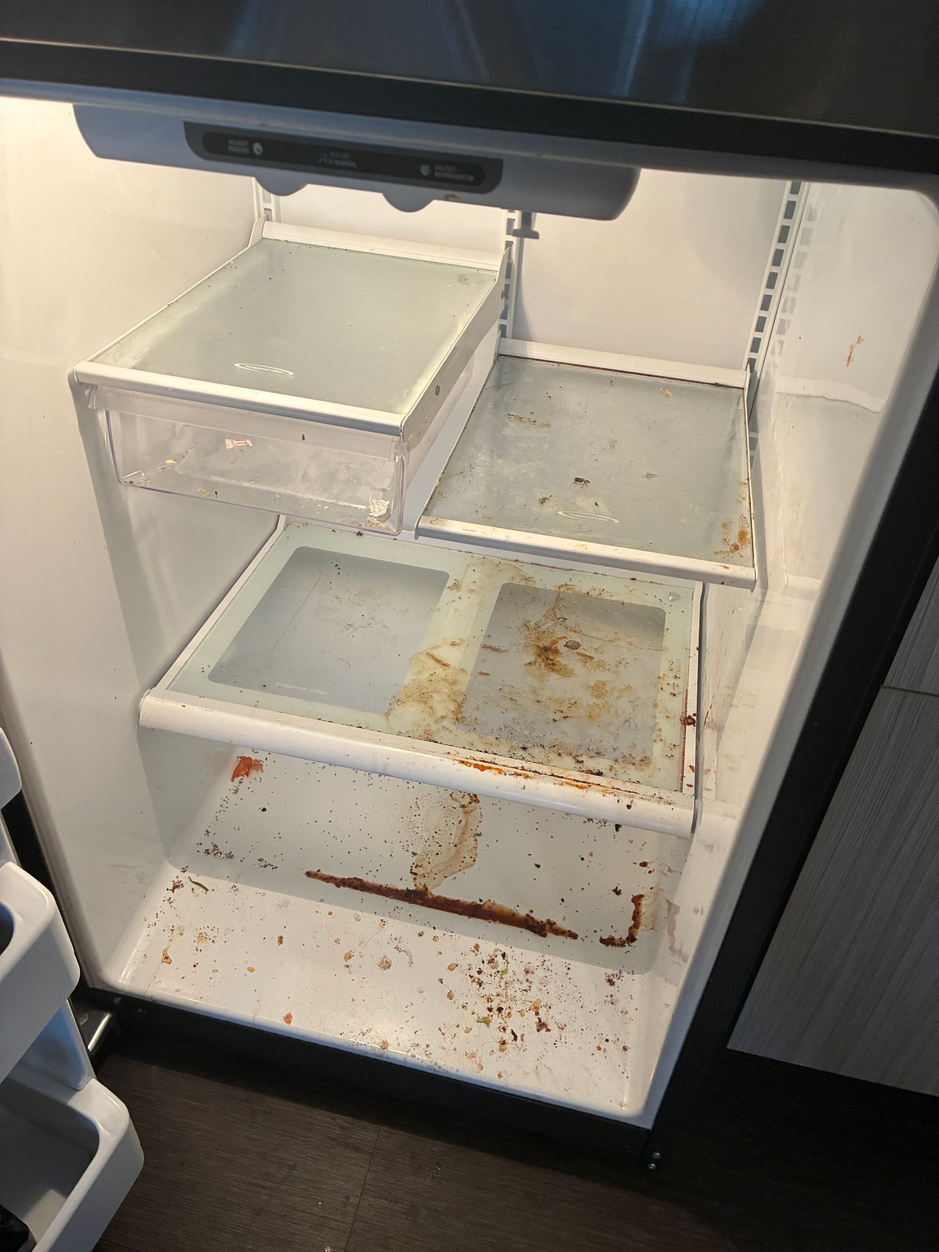 An open, dirty refrigerator interior with shelves and drawers needing cleaning.