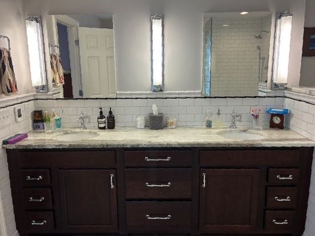 Bathroom with dark wood vanity, white tile backsplash, and three mirrors with vertical lights.