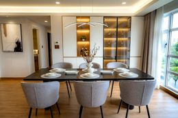 Dining room with a dark rectangular table, six gray chairs, and a lit display cabinet.