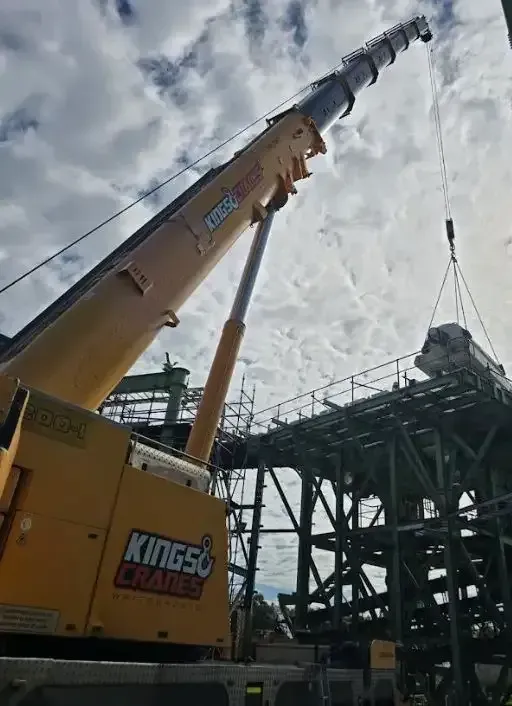 Yellow Kings Crane Lifting Equipment Beside a Steel Industrial Structure — Kings Cranes in Airlie Beach, QLD