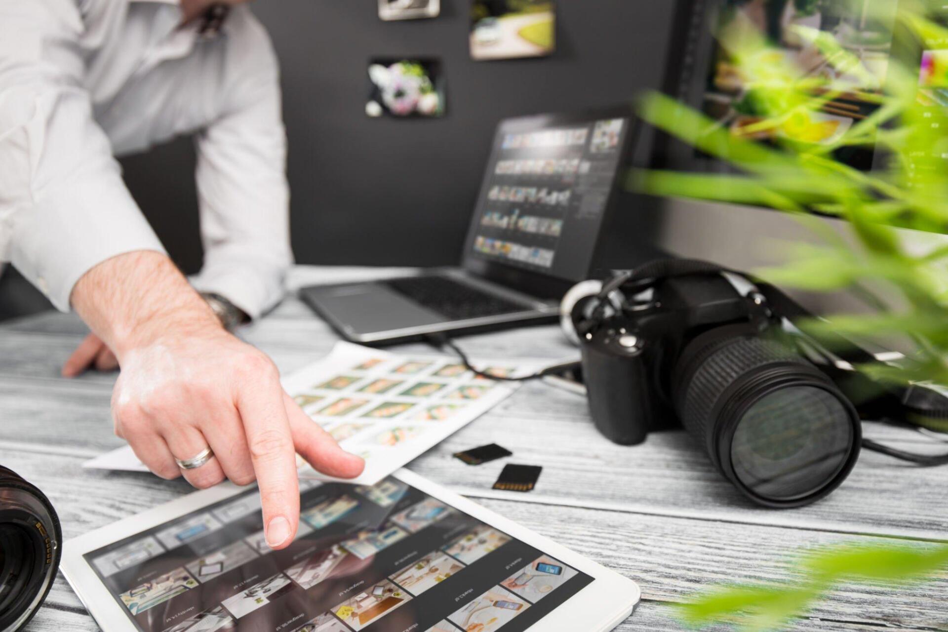 A man is pointing at a tablet with a camera in the background.