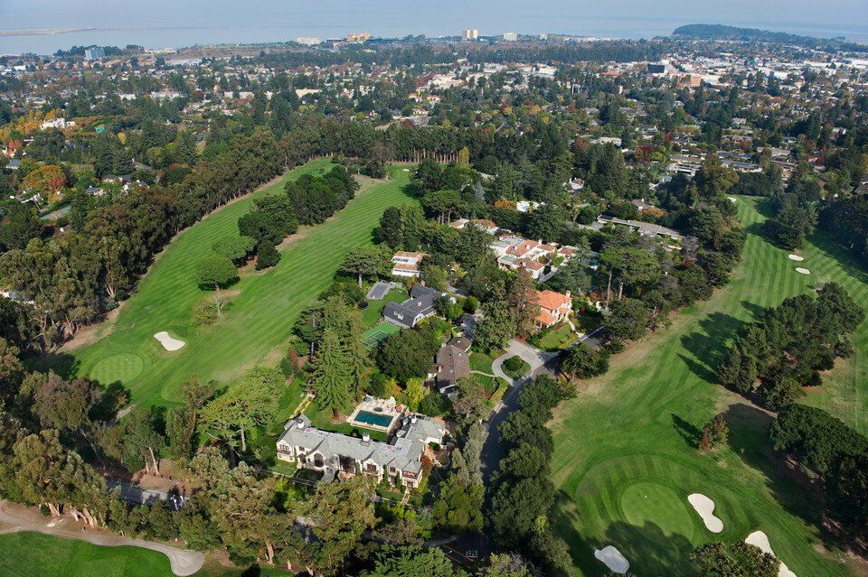 An aerial view of a golf course with houses in the background