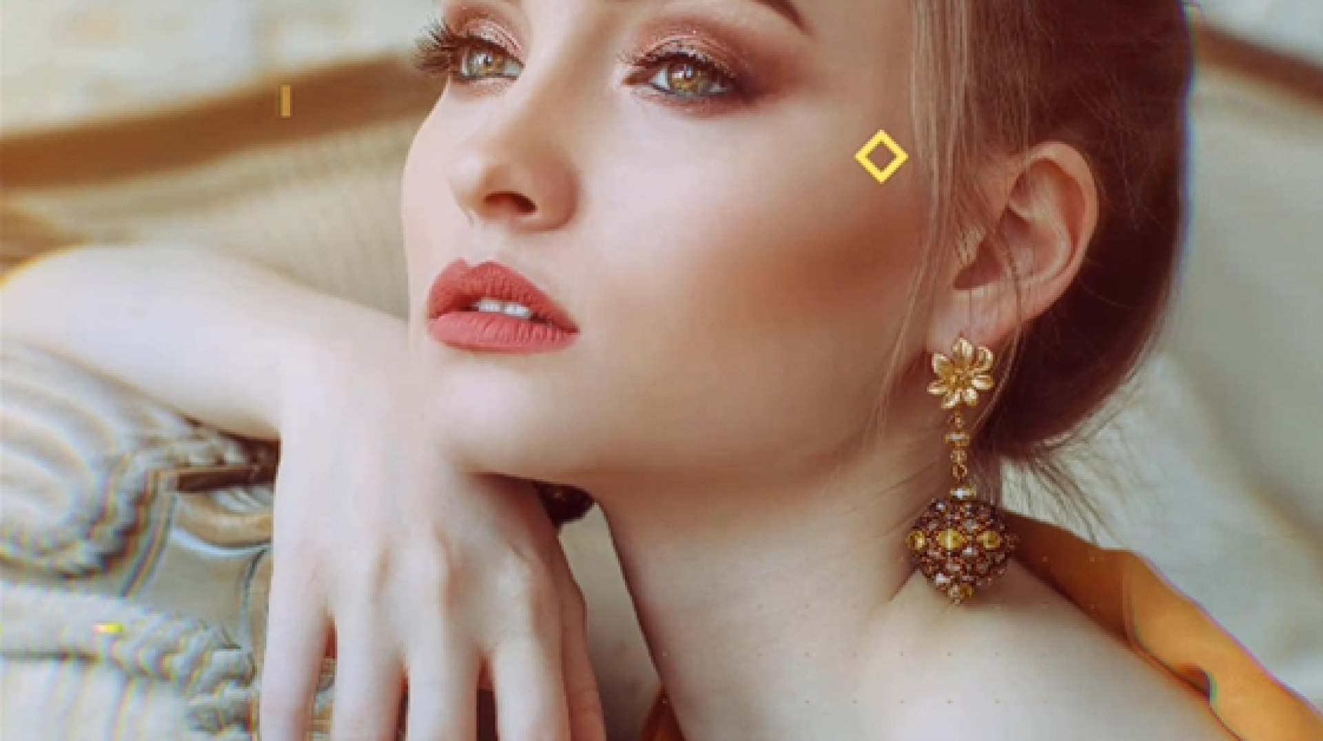 A close up of a woman wearing earrings and a diamond on her forehead.
