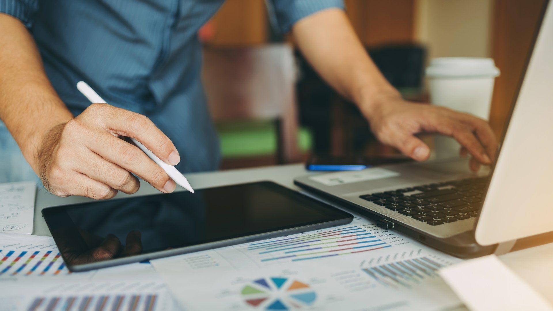 A man is using a tablet and a laptop at the same time.