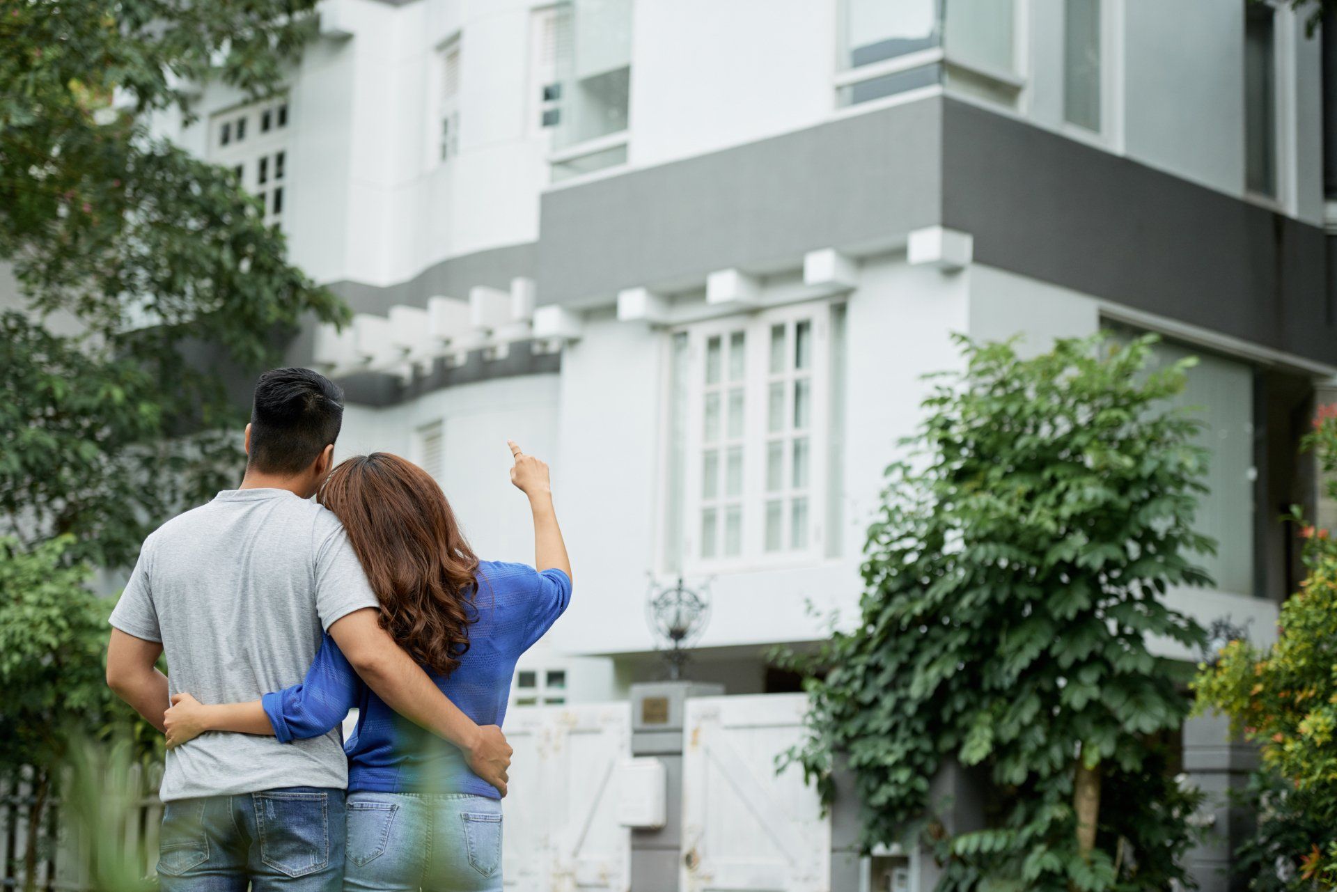 A man and a woman are standing in front of a large white house.