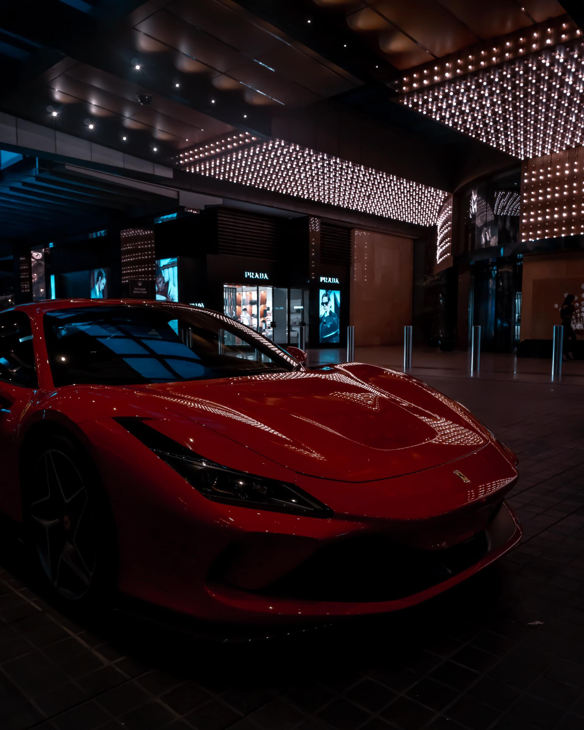 A red sports car is parked in front of a building at night.