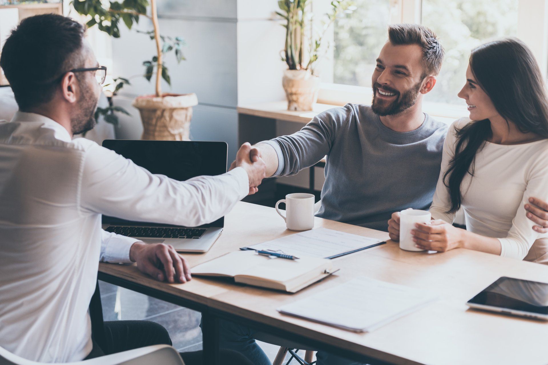 A man and a woman are shaking hands while sitting at a table.