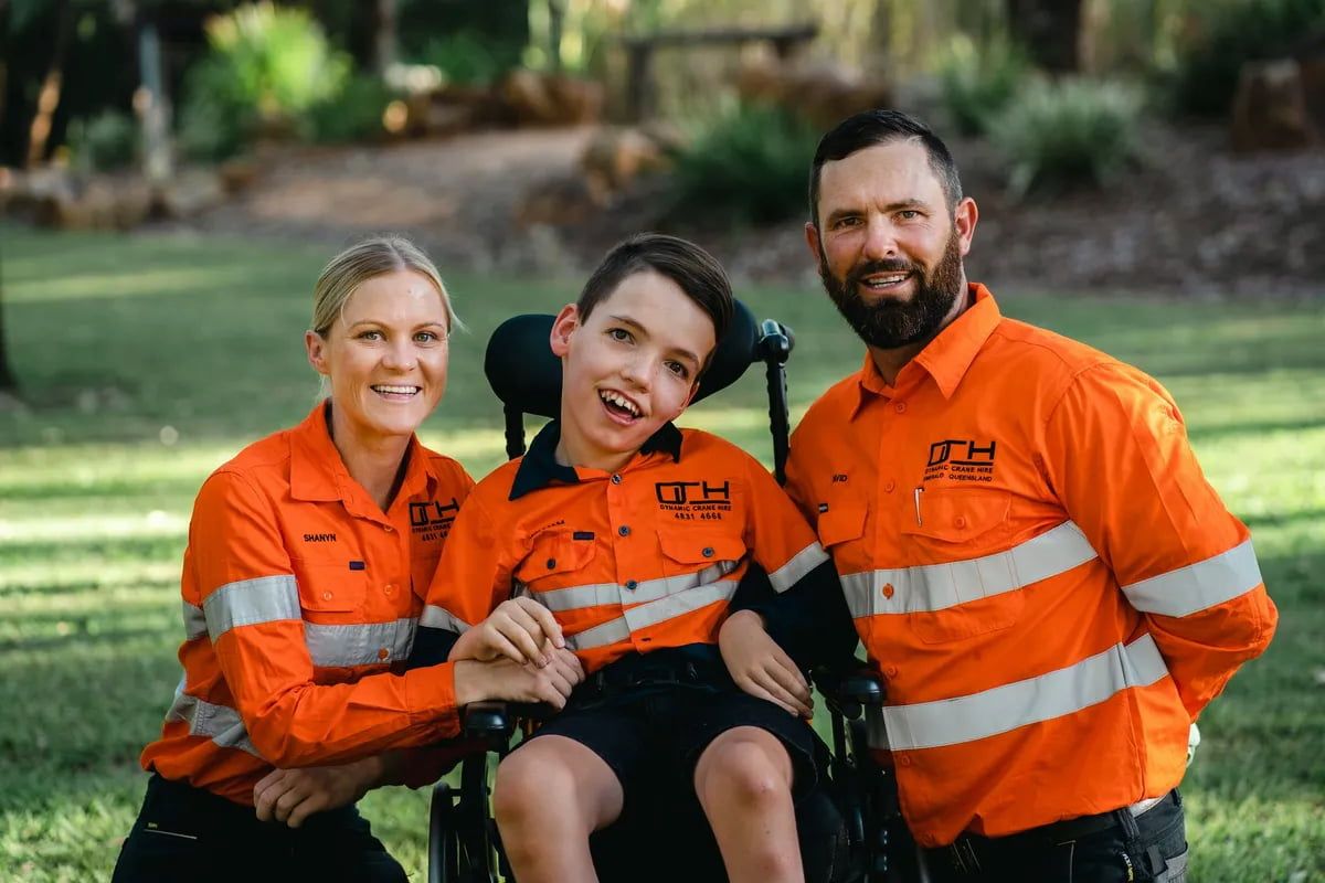A Man And Woman Are Posing For A Picture With A Boy In A Wheelchair — Dynamic Crane Hire In Emerald, QLD