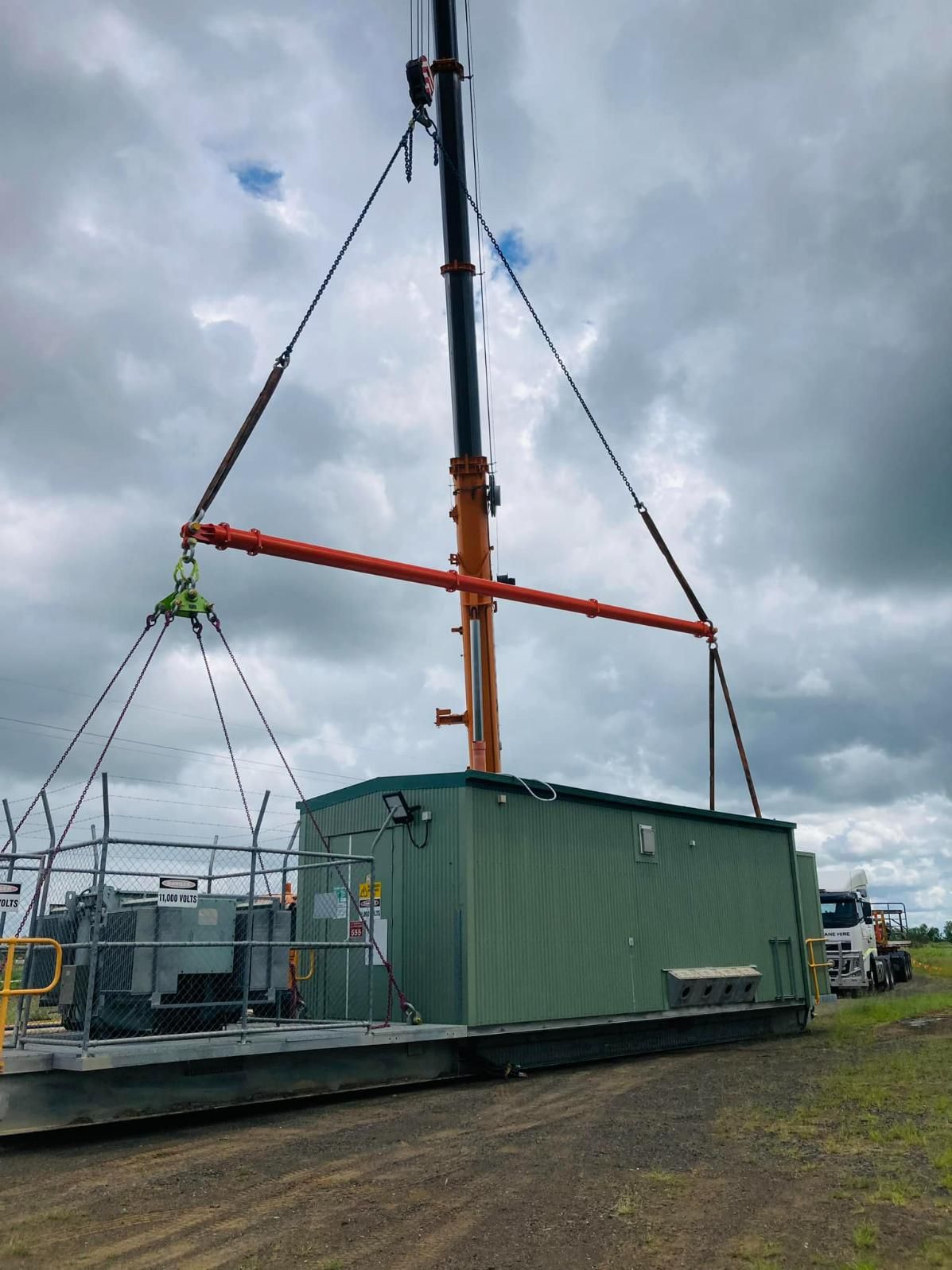 A Large Green Building Is Being Lifted By A Crane — Dynamic Crane Hire In Biloela, QLD