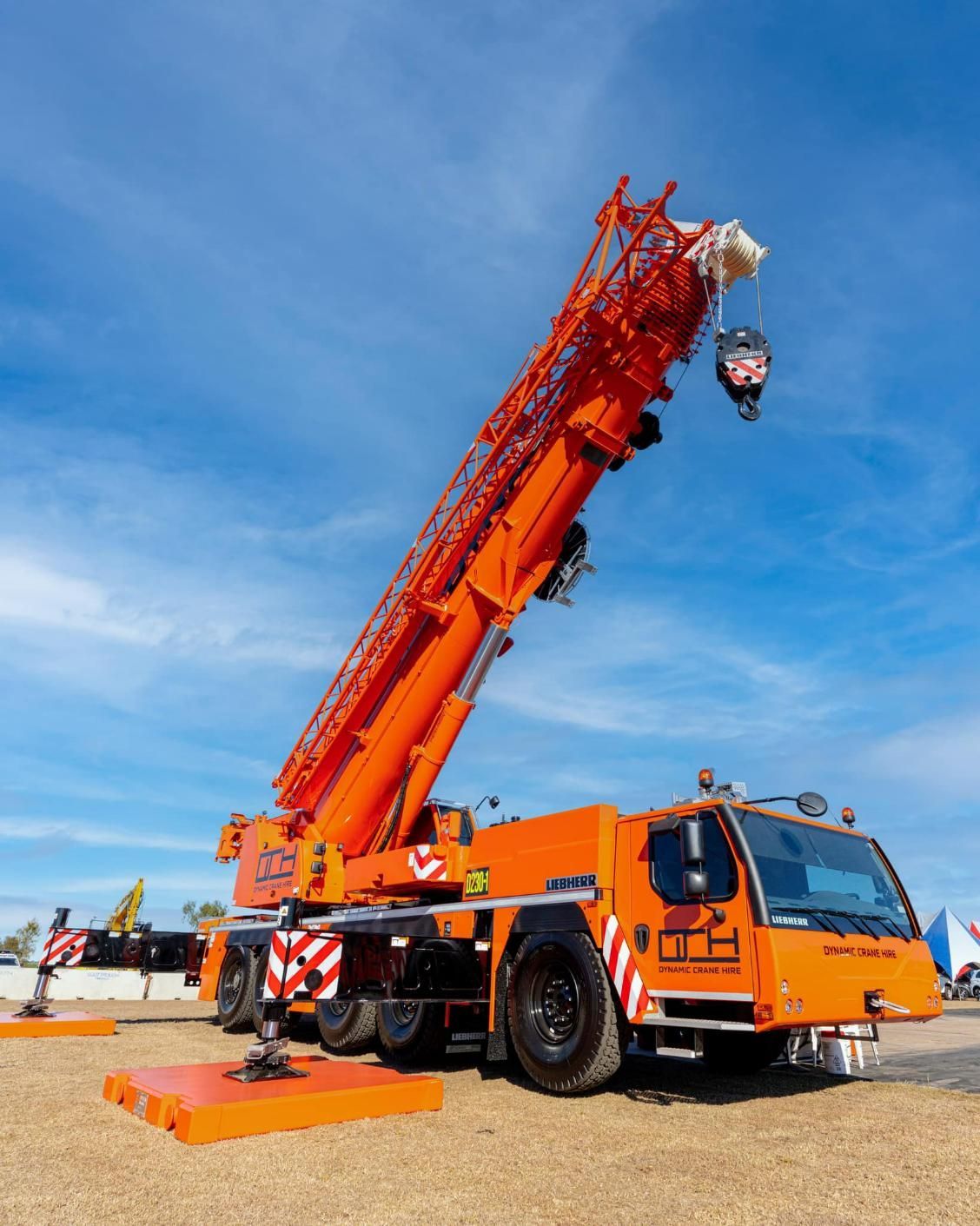 A Large Orange Crane Is Parked In A Dirt Field — Dynamic Crane Hire In Blackwater, QLD