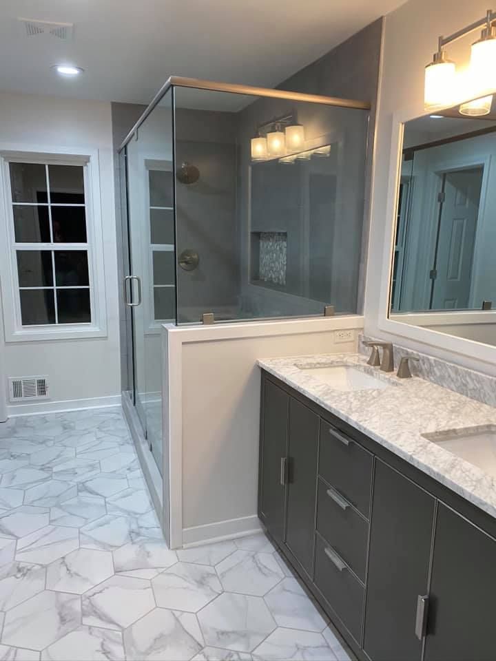 A bathroom with two sinks , a shower and a mirror.