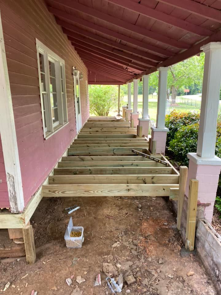 A wooden deck is being built on the side of a pink house.