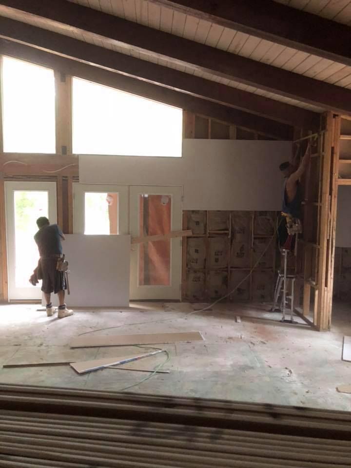A man is standing on a ladder in a room under construction.