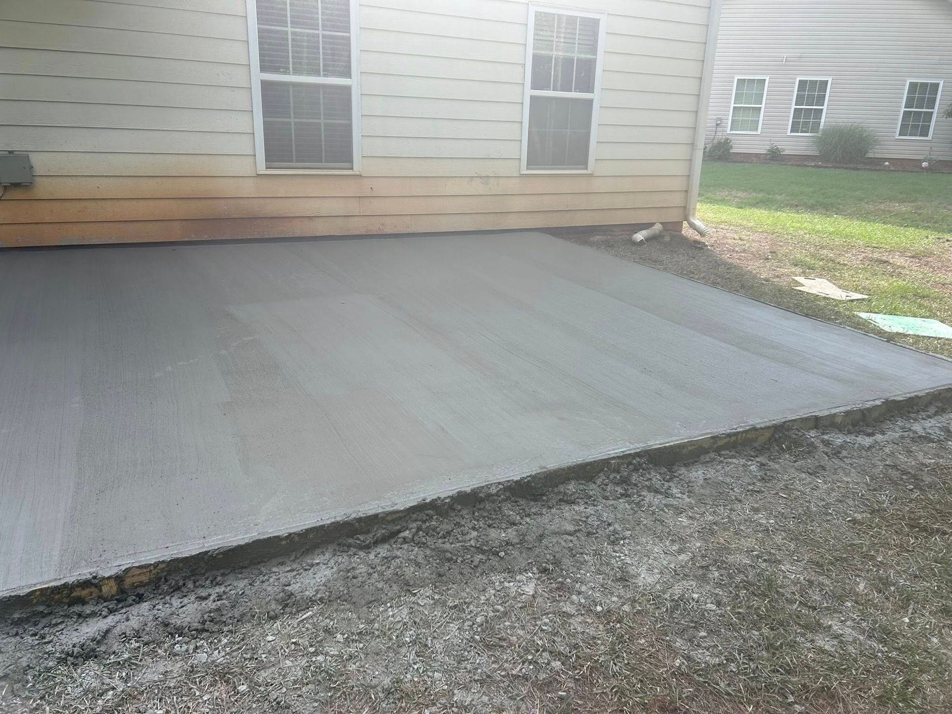 A concrete driveway is being built in front of a house.