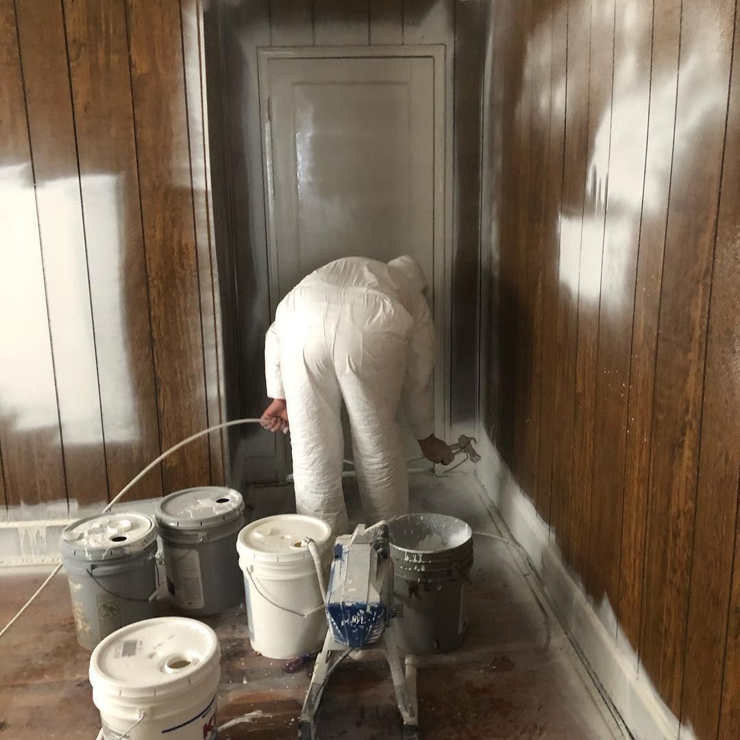 A man is painting a room with buckets of paint.