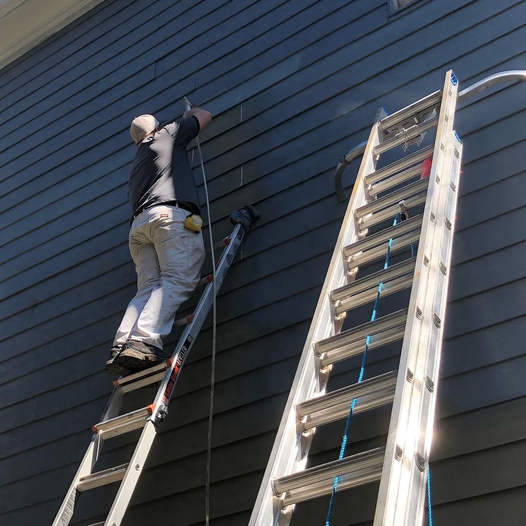 A man is standing on a ladder on the side of a building