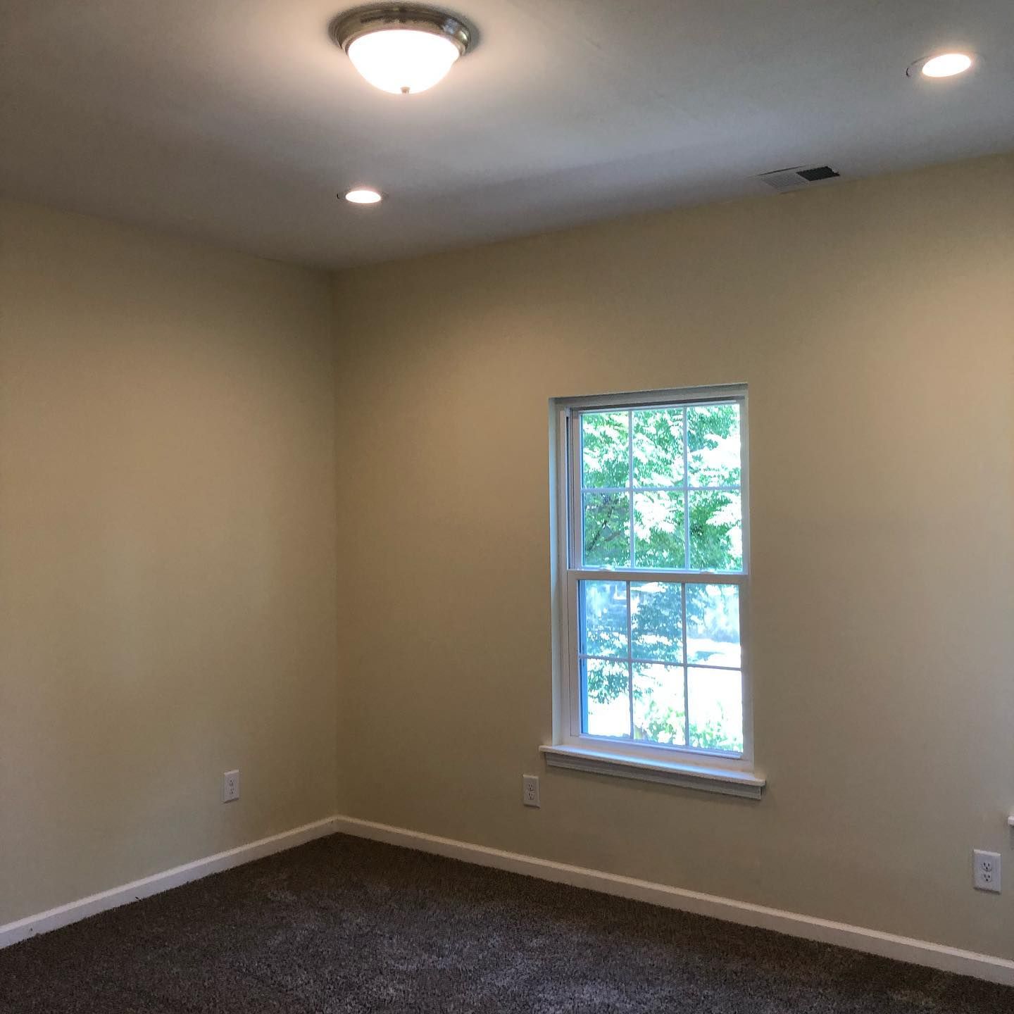 An empty room with a window and a light on the ceiling