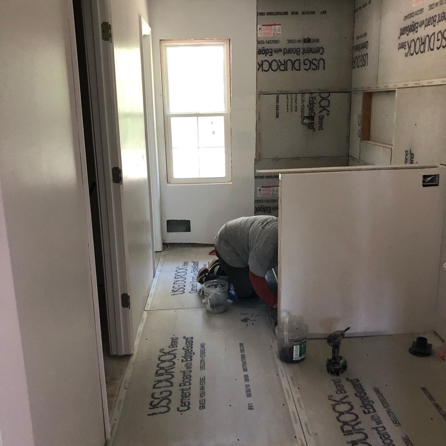 A man is kneeling on the floor in a hallway.